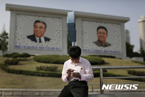 한 북한 남성이 지난 2015년 5월5일 평양의 김일성과 김정일의 대형 초상화 앞에서 스마트폰을 사용하고 있다. 북한은 스마트폰에 대한 100% 도청을 자신하고 있으며 북한 휴대전화는 국내에 국한된 인트라넷 연결만 가능한 외부 인터넷과의 연결은 불가능하다고 일본 아사히신문이 24일 보도했다.